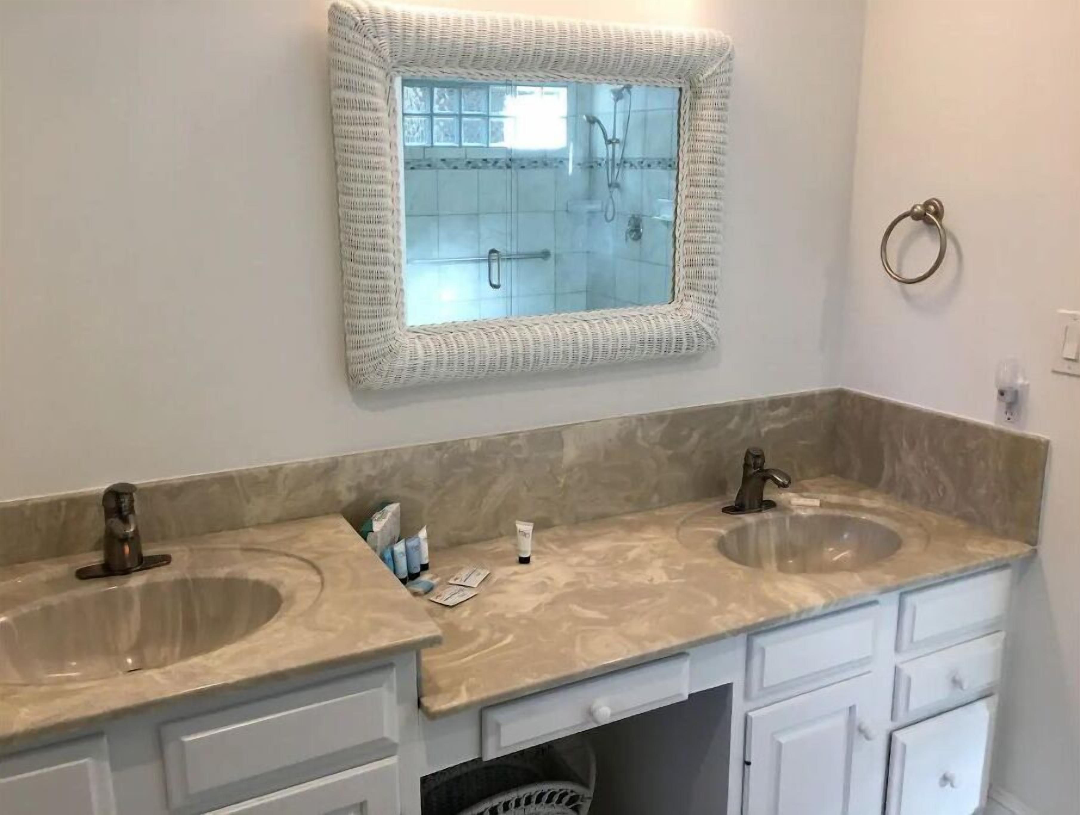 A bathroom with two sinks, a mirror, and a towel ring.