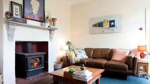 A living room with a fireplace, a sofa, a coffee table, and a painting on the wall.