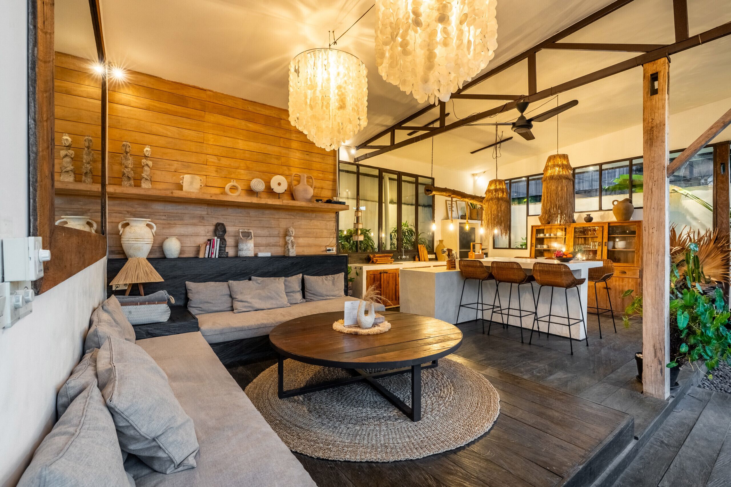 Un intérieur moderne avec un mur en bois, une table basse ronde, un canapé et un coin cuisine doté de tabourets de bar.
