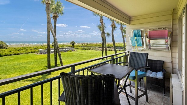 A balcony with wicker furniture, a view of the ocean, and a window with a curtain. - Direct Oceanfront View - Beachfront Villa (Hilton Head Island)