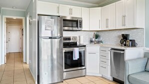 A modern kitchen with stainless steel appliances, white cabinets, and a tiled floor. - Direct Oceanfront View - Beachfront Villa (Hilton Head Island)