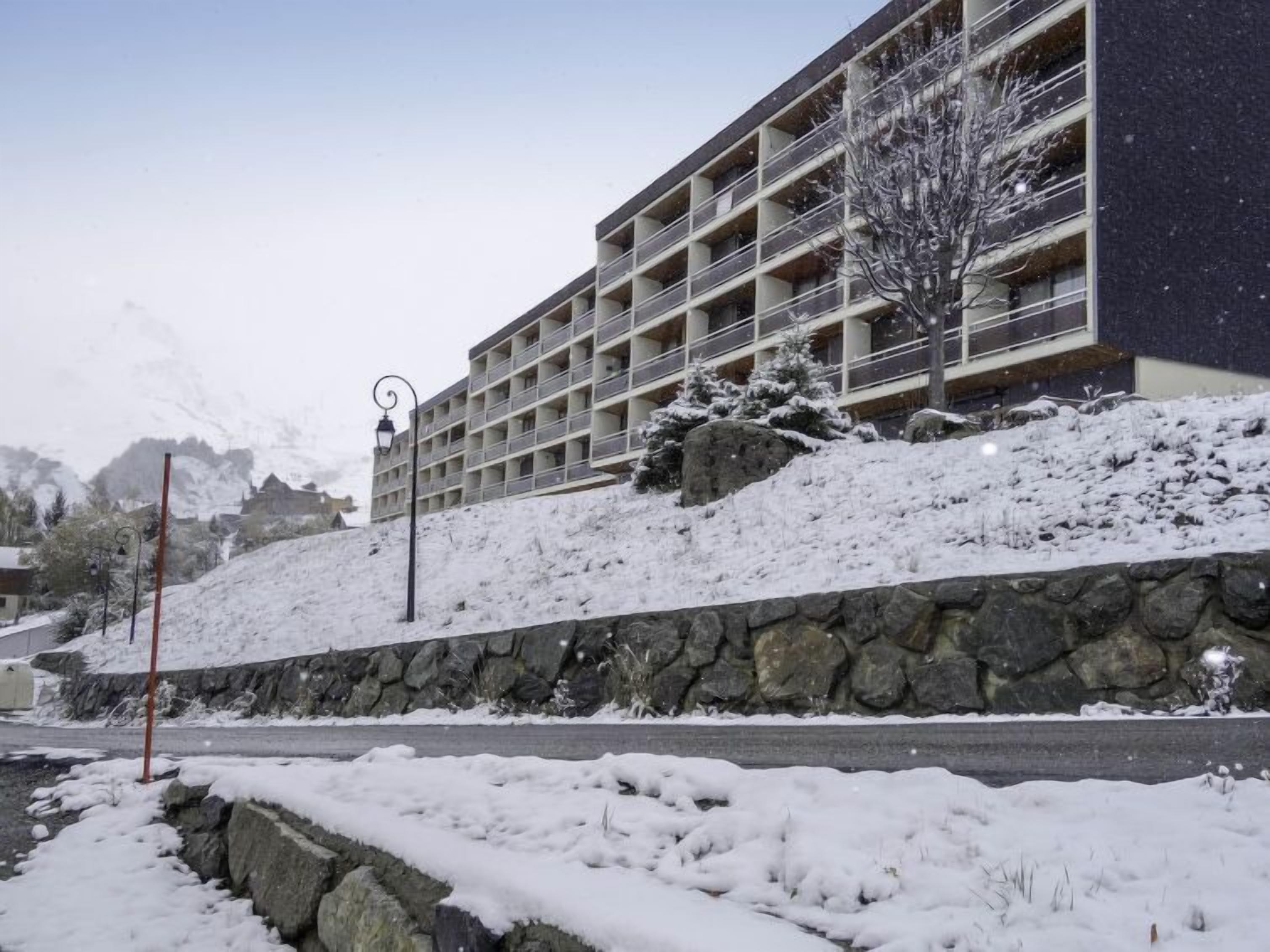A multi-story hotel with a stone retaining wall and a snow-covered landscape.