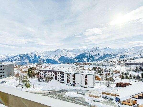 A snow-covered town with a prominent building in the foreground and a mountain range in the background.