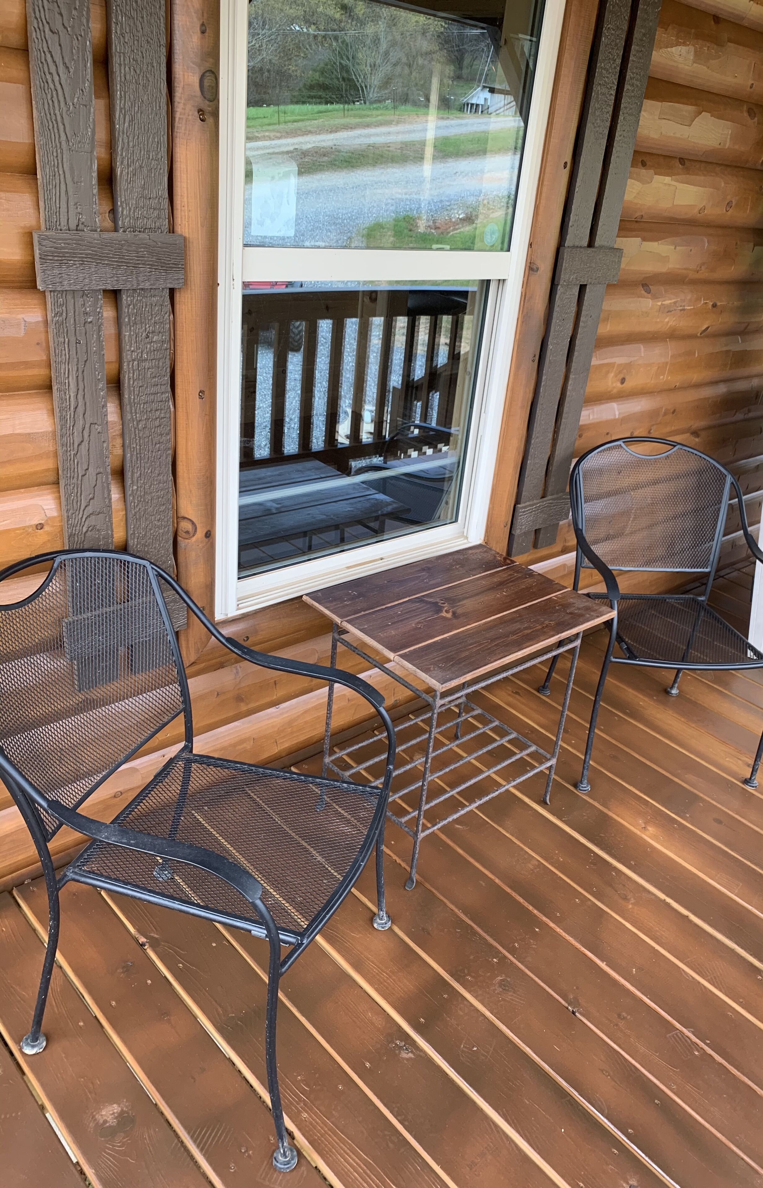 Une terrasse en bois avec deux chaises en métal et une petite table.