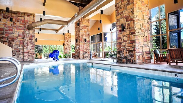 A swimming pool with stone pillars, outdoor seating, and large windows. - #1312 Winter and Summer Adventure Awaits! (Brian Head)