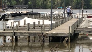 Une jetée en bois s’étendant dans une étendue d’eau, avec des bateaux amarrés à proximité.