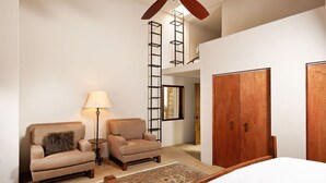 A bedroom with a bed, two armchairs, a floor lamp, a wooden wardrobe, and a ladder leading to an upper level. - Remodeled Penthouse in the heart of Downtown Basalt, historic 1900's Building  (Basalt)