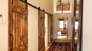A hallway with wooden sliding doors, a patterned rug, and a ceiling-mounted horse sculpture. - Remodeled Penthouse in the heart of Downtown Basalt, historic 1900's Building  (Basalt)