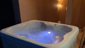 A hot tub with a built-in heater, surrounded by a wooden deck and a brick wall. - Buckeye Mountain Dreams (Sevierville)