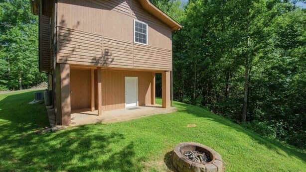 A two-story house with a front porch, a small attached garage, and a fire pit in the yard. - Buckeye Mountain Dreams (Sevierville)