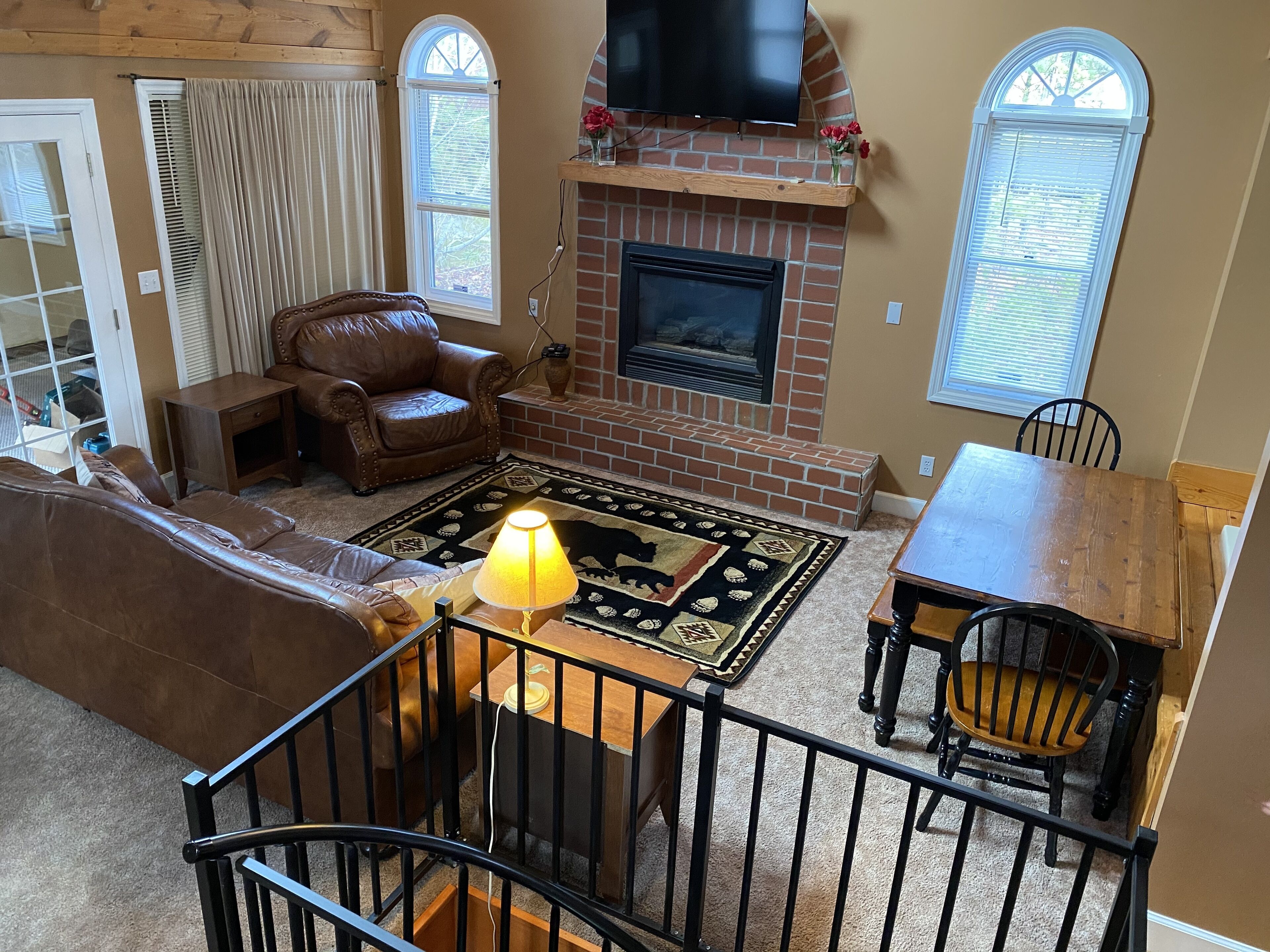A cozy living room with a fireplace, leather furniture, and a TV mounted above it.