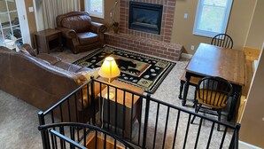 A cozy living room with a fireplace, leather furniture, and a TV mounted above it. - Buckeye Mountain Dreams (Sevierville)