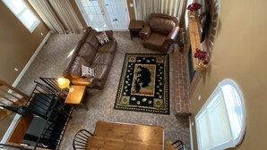 A spacious living room with a brown leather sofa, a wooden coffee table, and a patterned rug. - Buckeye Mountain Dreams (Sevierville)