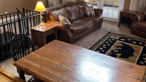 A cozy living room with a wooden coffee table, leather sofa, and a patterned rug. - Buckeye Mountain Dreams (Sevierville)