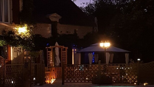 A swimming pool with a wooden deck and a covered seating area.