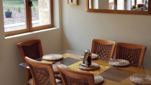 A dining area with a wooden table and chairs, a small decorative item on the table, and a window with a view of the outdoors.