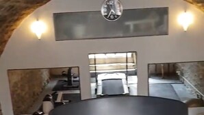 A gym with exercise equipment, a clock, and mirrors on the walls.