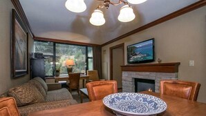 Un coin repas avec une table en bois, une assiette décorative et un téléviseur fixé au-dessus d’une cheminée.