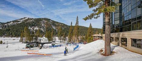 A ski slope with a modern building and a mountain in the background.