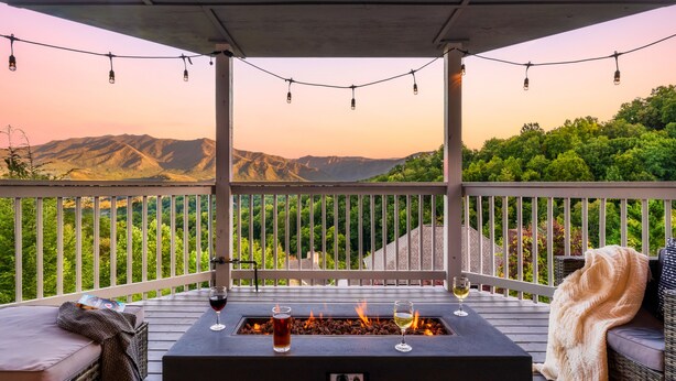 Eine Terrasse mit Feuerschale, zwei Weingläsern und Blick auf die Berge.