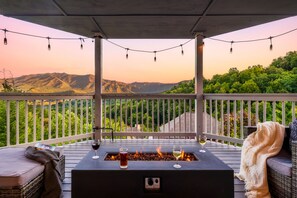 Une terrasse avec un foyer intégré, deux verres de vin et une vue sur les montagnes.