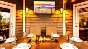 Ein Essbereich mit Kaminfeuer, Holzwänden und einem montierten Fernseher, der eine Landschaft zeigt.