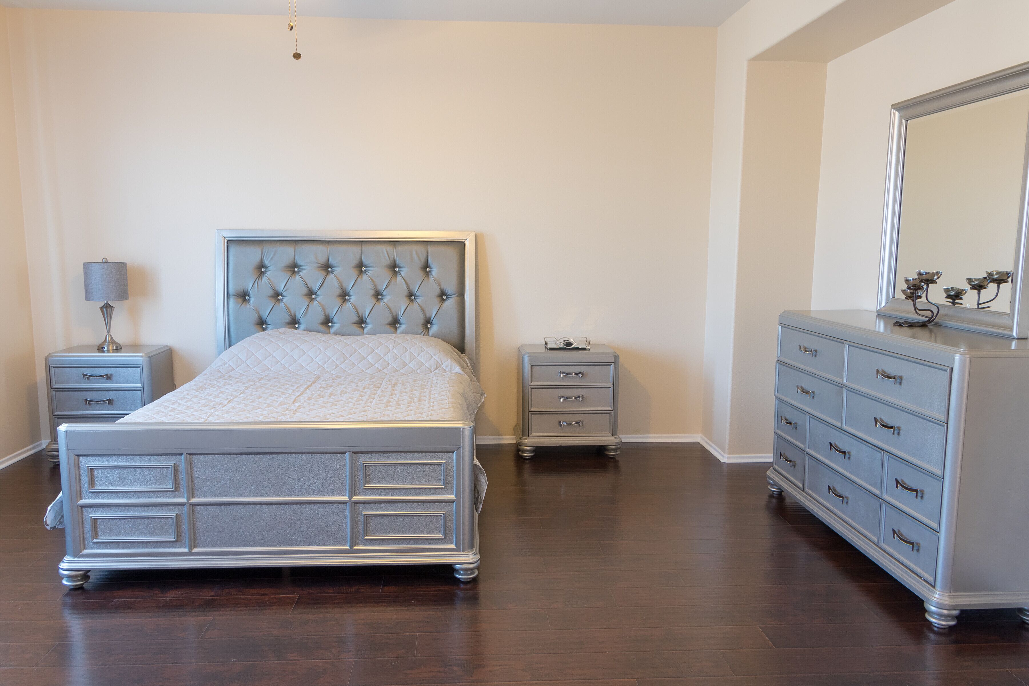 Un dormitorio con una cama, dos mesitas de noche, un aparador y un espejo.
