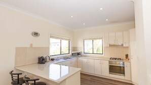 A modern kitchen with a central island, built-in microwave, stove, and oven. - Alaska - 8 Poley Cow Lane (Jindabyne)