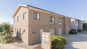 A two-story apartment building with a beige exterior, multiple windows, and a small driveway. - Alaska - 8 Poley Cow Lane (Jindabyne)
