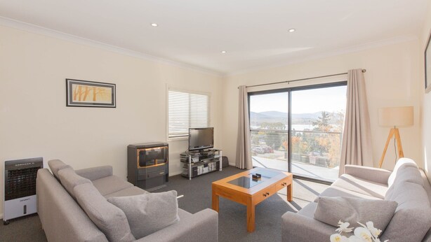 A modern living room with a sofa set, a coffee table, a TV, and a fireplace. - Alaska - 8 Poley Cow Lane (Jindabyne)