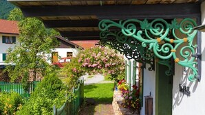 Ein Weg führt zu einem Haus mit grünem Zaun, einer Steinmauer und einem Blumenbeet.