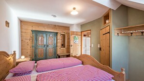 Ein Zimmer mit einem hölzernen Bett, einem Holzschrank und einer Tür mit einem Fenster.