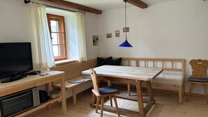 Ein Zimmer mit einem Holztisch, einer Bank und einem Fernseher.