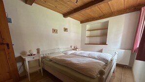 Ein Schlafzimmer mit einem hölzernen Bett, einem weißen Schreibtisch, einer Heizung und zwei gerahmten Bildern an der Wand.