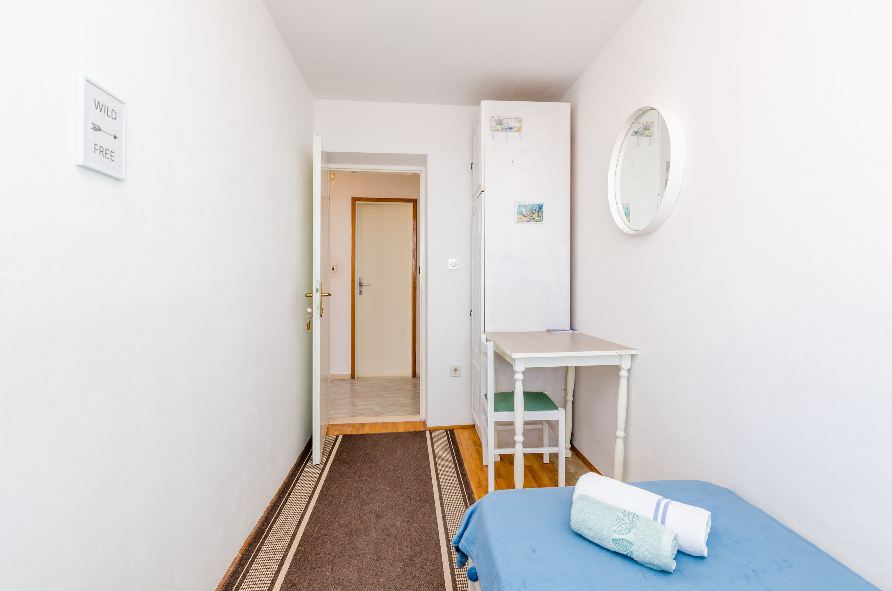 Una habitación pequeña y limpia con cama, escritorio y espejo.