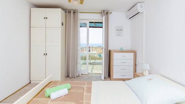 A bedroom with a bed, a wardrobe, a desk, and an air conditioning unit. - Rooms Nikola (Dubrovnik)