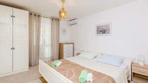 A hotel room with a bed, a wardrobe, a desk, a nightstand, and a window with curtains. - Rooms Nikola (Dubrovnik)