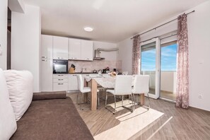 A modern apartment with a dining area, kitchen, and a balcony with curtains. - Pool & Garden Apartment Bakija 2 (Pakostane)
