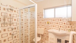 A bathroom with a shower, toilet, sink, and a window. - Charvel - 2/35 Gippsland Street (Jindabyne)
