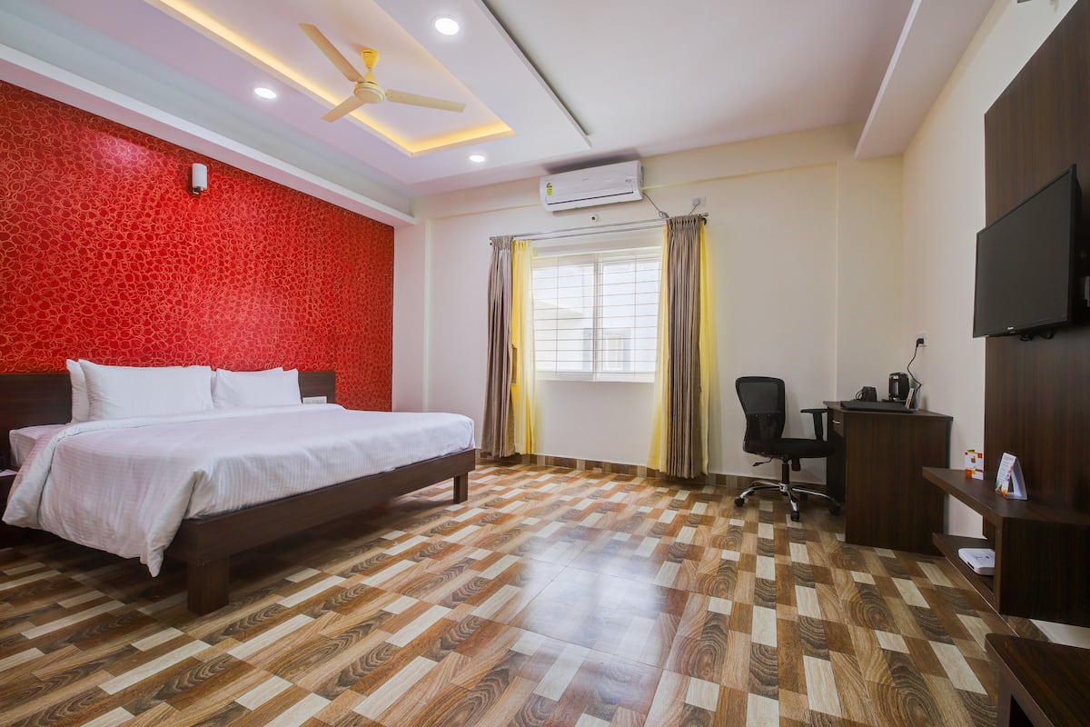 A hotel room with a bed, desk, chair, and TV.