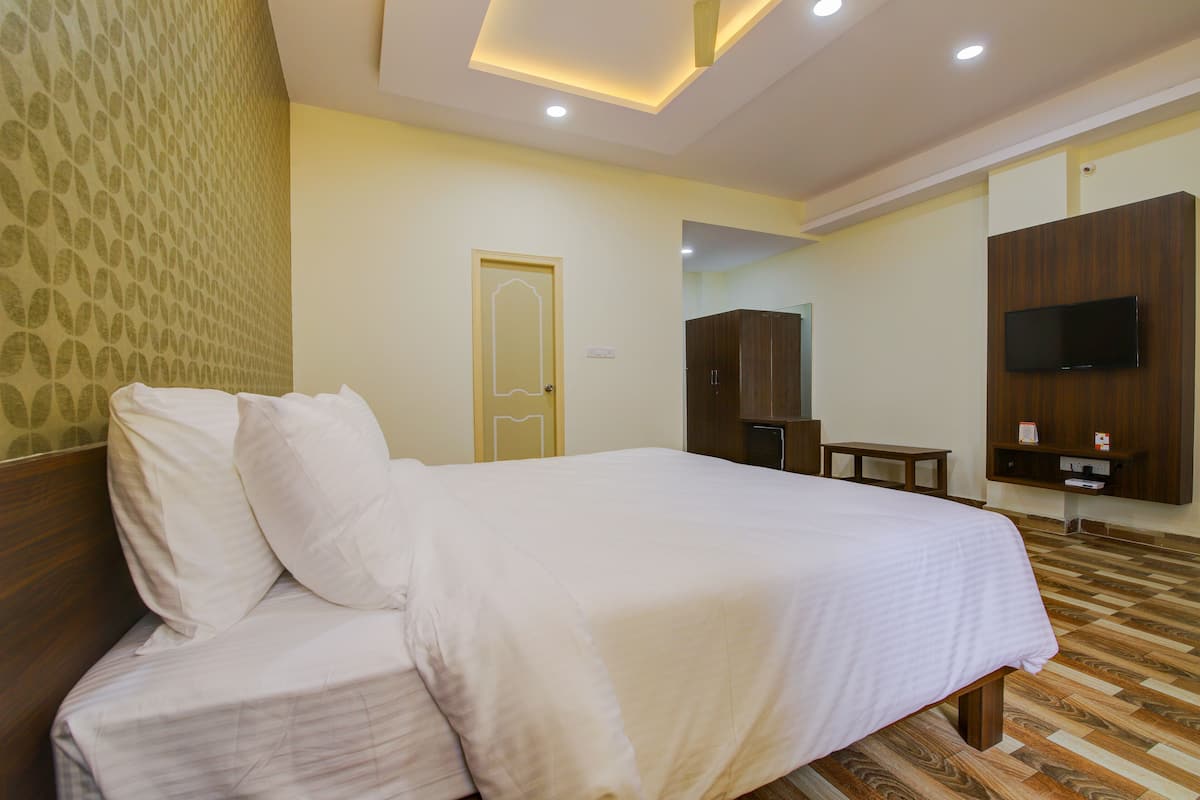 A hotel room with a large bed, a desk, a television, and a wardrobe.