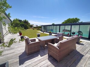 Eine Terrasse im Freien mit Rattanmöbeln, einem verglasten Bereich und einem Pool.