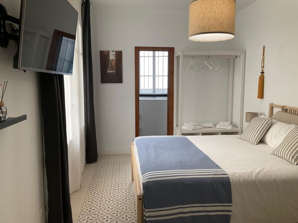 Una habitación de hotel con cama, televisión, armario y lámpara colgante.