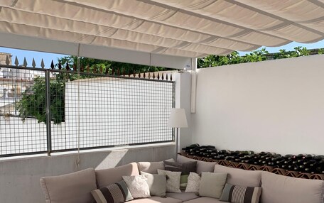 A covered outdoor seating area with a sofa, chairs, and a table.