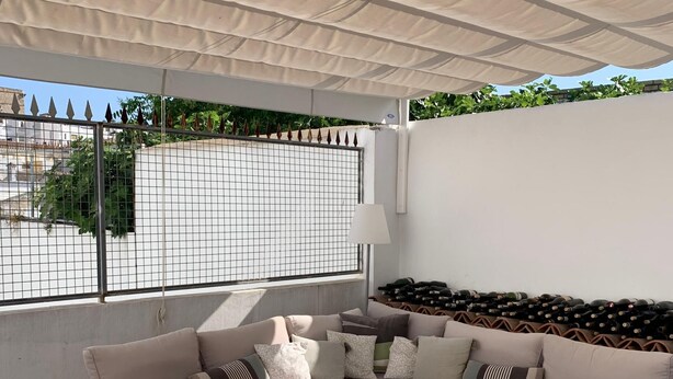 Un espacio de estar al aire libre techado con un sofá, sillas y una mesa.