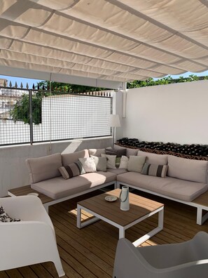Un espace extérieur aménagé, abrité et doté d’un canapé, de chaises et d’une table.
