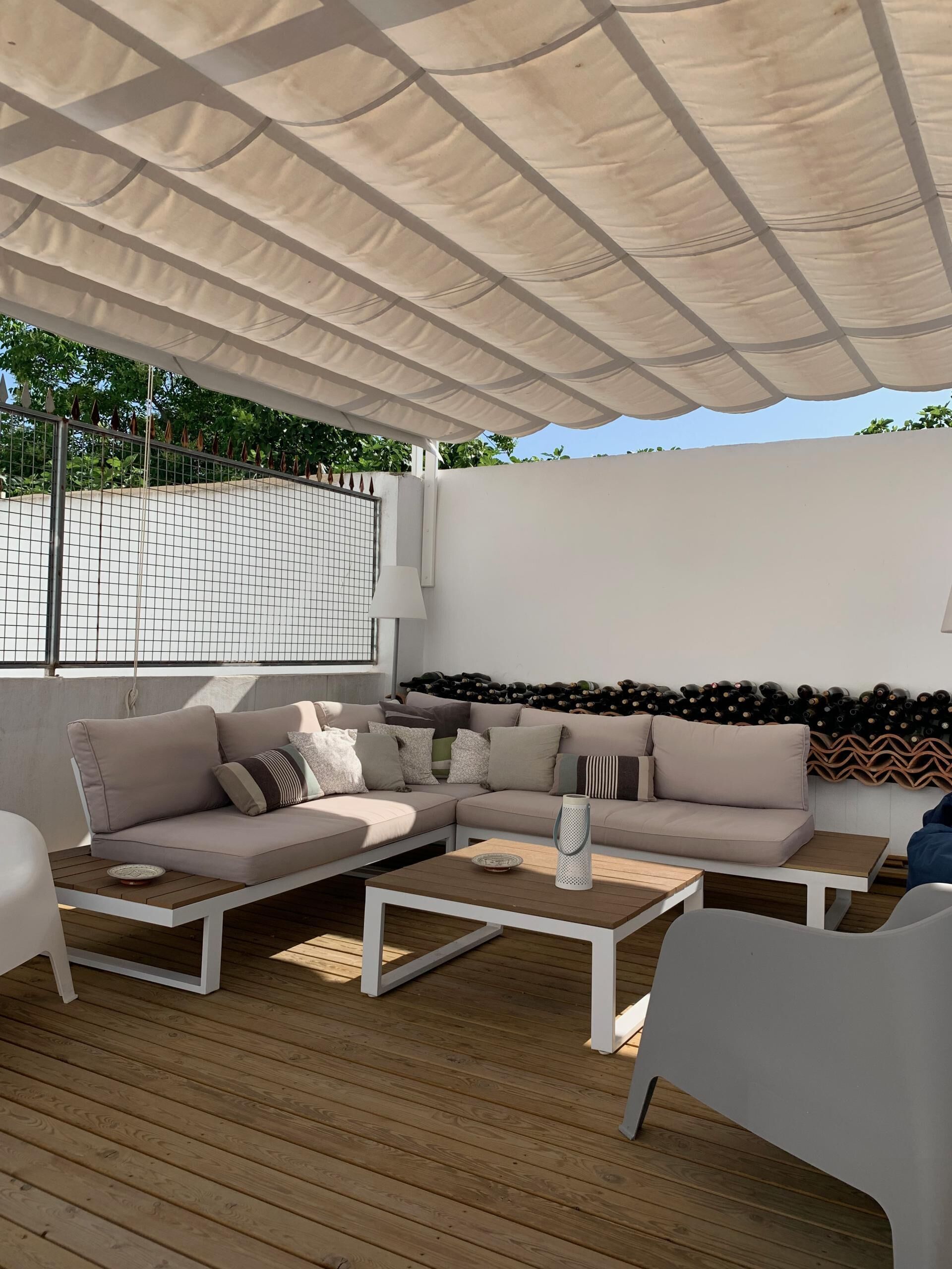 An outdoor seating area with a cushioned sofa, a coffee table, and a white chair.