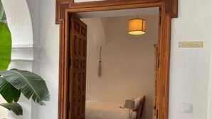 Un dormitorio pequeño y acogedor con una cama individual, una mesita de noche, una lámpara colgante y un marco de puerta de madera.