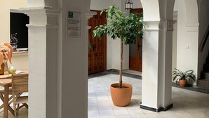 Un espacio interior amplio con paredes blancas, vigas de madera y suelo de baldosas.