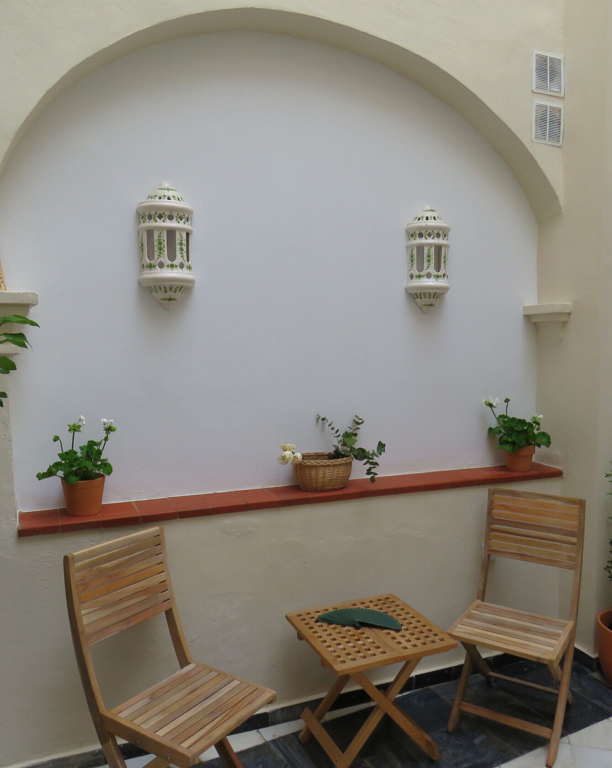 Een klein terras met twee houten stoelen, een tafel en potplanten.